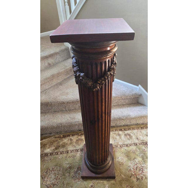 A vintage pedestal column boasts a unique fluted design and carved leaf and flower accents that add a touch of...