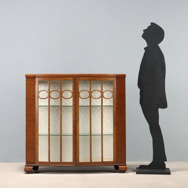 Art Deco display cabinet in mahogany veneer. Curved front with a pair of tripartite glass doors, glass sides, and curved...