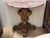 A pair of Italian console tables, each with a demilune top of rose and cream veined marble raised on a boldly carved...