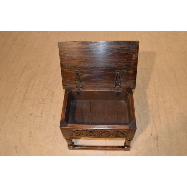 Late 19th century oak stool from England with a lift-top and lovely hand carved panels on three sides and pegged...