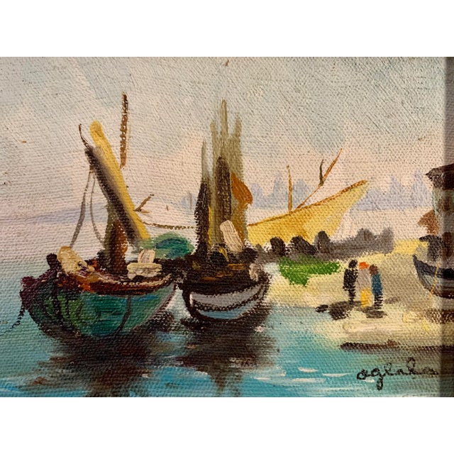 Depicting a landscape view of boats and people by a boat dock. Housed in a gilded velvet cover wooden frame. Artist signed...