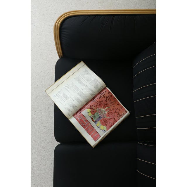 Vintage loveseat sofa defined by its sculptural ribbed wood arms and black upholstery. Subtle pinstriped back cushions...