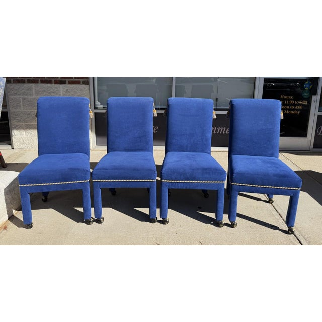 The four royal blue upholstered chairs bring a touch of opulence, highlighted by gold-and-blue cord trim and decorative...