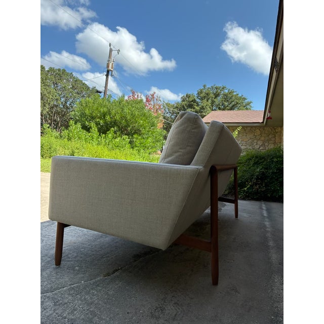 3 seat sofa. Sofa features an exposed solid walnut frame that wraps around the back to support the seating area. It is...