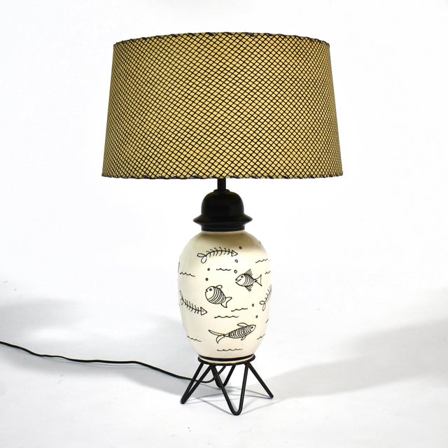 This playful table lamp has several qualities of 1950s design: the ceramic body has an urn-like form, is decorated with a...