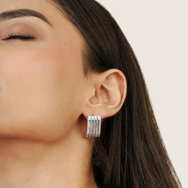 Crafted in 925 sterling silver, these elegant bar earrings feature natural round blue topaz gemstones measuring 2 mm,...