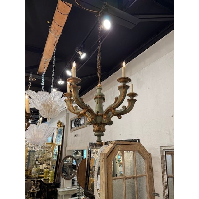 The product is a 19th-century Italian carved and painted chandelier. Featuring an ornated chandelier in green and gold....