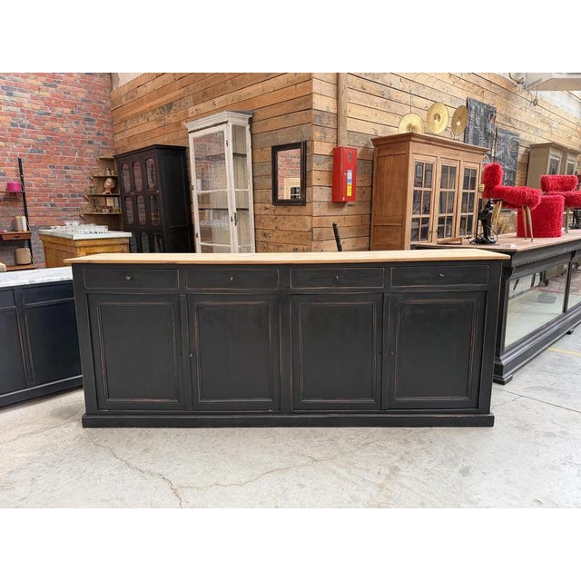 This antique sideboard made of solid cherry wood has been completely restored. It features a natural wood top and a black-...