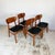 A set of four dining chairs with curved teak-veneered plywood backrests. Each back is cut from a sheet with strong figure,...
