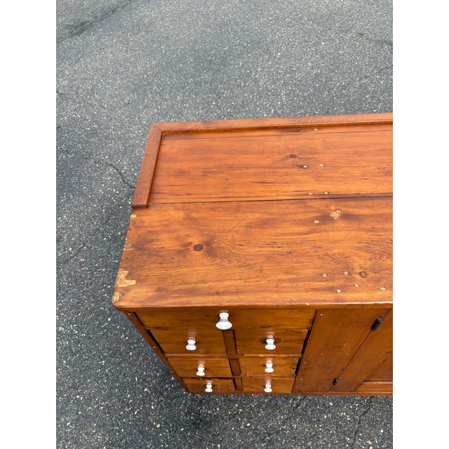 This mid to late 1800's apothecary cabinet is a beautiful antique piece crafted from wood with a warm honey stained...