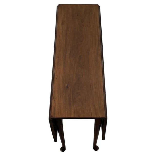 A refined 18th-century English gateleg table, finely crafted from walnut and distinguished by its practical drop-leaf...