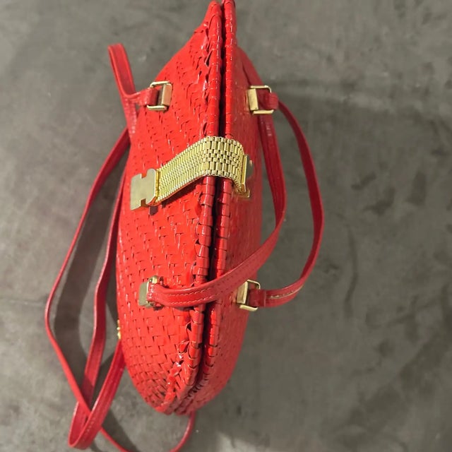 This stunning vintage high quality handbag from the 1960s features a striking woven wicker design in a vibrant, bold red....