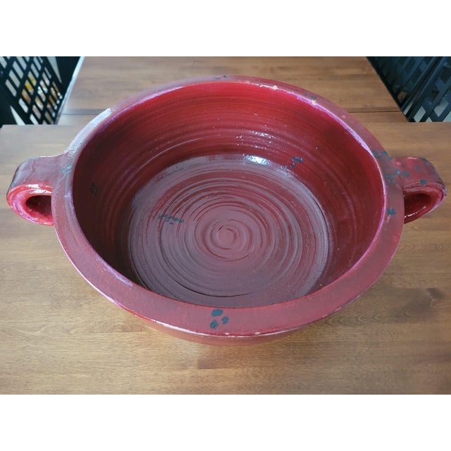 This heavy red clay bowl features a rich glossy glaze, accented with black decorative spots and beautifully sculpted loop...
