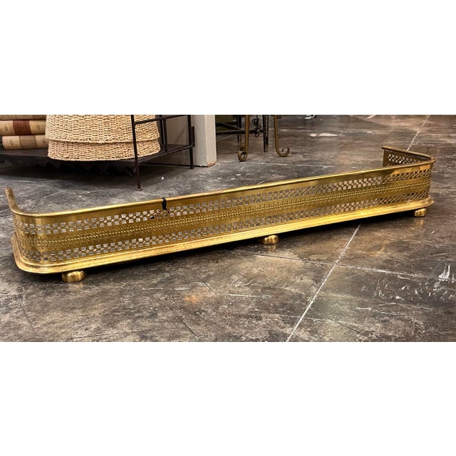 A George III style English pierced brass fireplace fender from the Late 19th-Early 20th Century. This stunner features a...