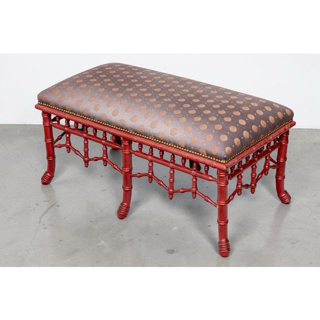 A striking vintage faux bamboo pagoda bench featuring an elaborate red lacquered frame with turned spindle fretwork,...