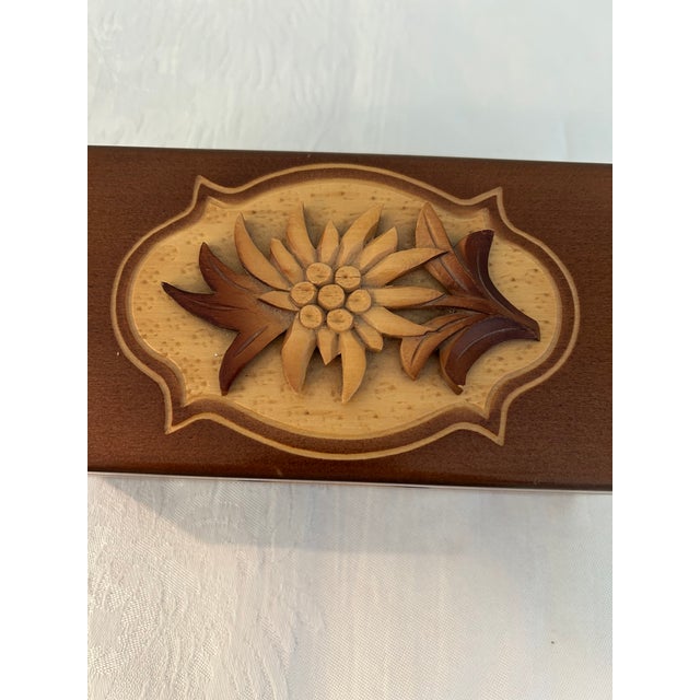 Charming vintage walnut wood music box featuring a hand-carved Edelweiss flower on hinged lid in walnut and maple wood....