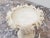 A decorative alabaster centerpiece featuring a finely carved rim adorned with leaf ornamentation. The central stem...