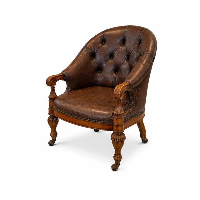 Set of four English Regency Revival tufted leather library chairs with carved hardwood arms and original casters. Rich...