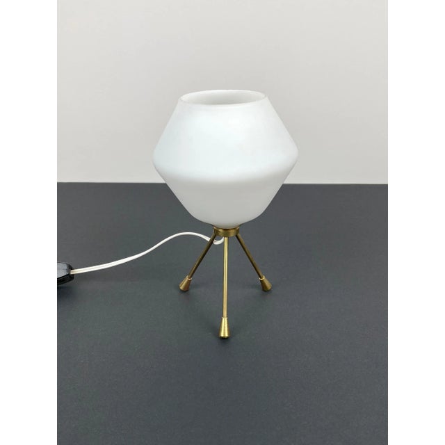 Tripod table lamp in brass and opaline glass. Made in Italy in the 1960s. Up to 250V (Europe/UK Standard).The wiring of...