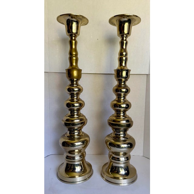 Here is a grand pair of brass candle holders that are over 25" tall. They feature a descending spool or stacked spool...