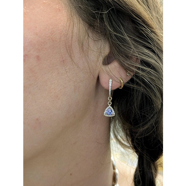 Dazzle in style with trillion tanzanite earrings framed by sparkling earth-mined diamonds. These dangle earrings are set...
