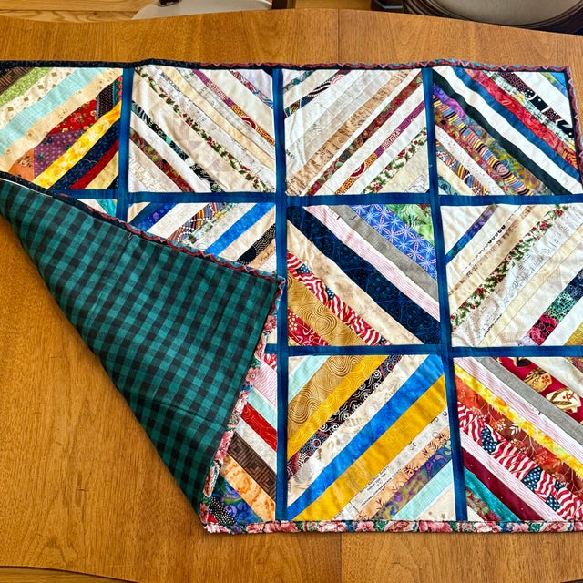 Handcrafted American folk art patchwork quilt featuring diagonally pieced blocks arranged in a grid, creating a bold...