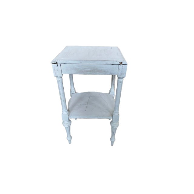 A Sheraton side table that is from the 1950's. This piece is white with an almost square shaped top that has been restored.