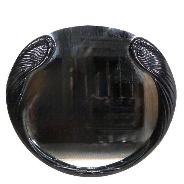 Extraordinary Hollywood Regency style wall mirror, having an Art Deco Revival stylized black lacquered frame which borders...
