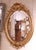 A refined antique French oval wall mirror crafted in carved giltwood circa 1860, showcasing the fluid and decorative...