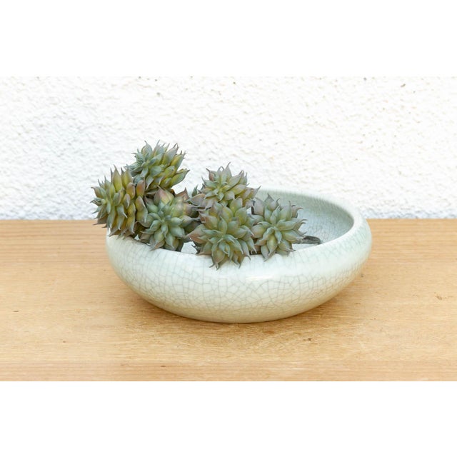 This low-profile ceramic vessel is a fine addition to an architectural tabletop collection, featuring a soft celadon-style...