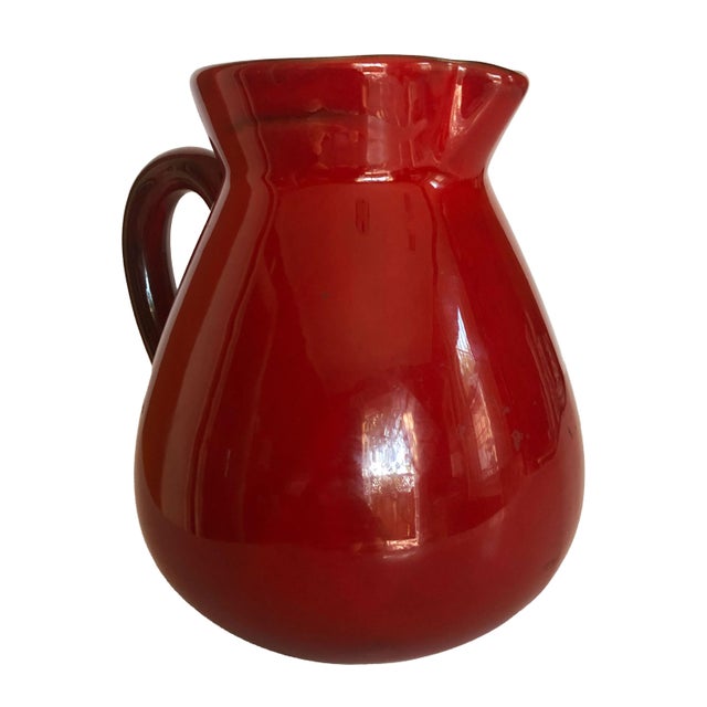 A bold and beautiful French ceramic pitcher finished in a striking crimson red glaze that commands attention in any...