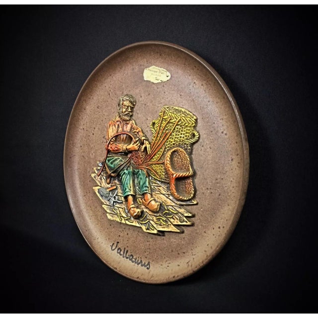 This unique ceramic plate from Vallauris showcases a detailed bas-relief of a weaver, capturing the essence of fine...