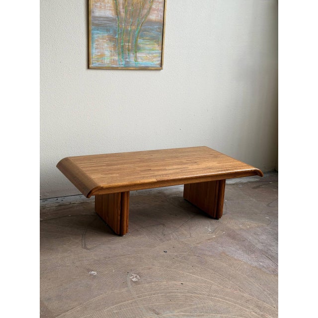 Striking postmodern coffee table in oak with distinctive waterfall edges and substantial block legs. The low, wide...
