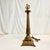 Thus is a cast brass lamp from the Mid-Century. It features Neoclassical design elements with a tall Grecian pillar...