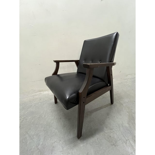 Understated vintage 1960s or 70s Armchair: Black, minimally button-tufted, faux leather upholstery above unassuming...
