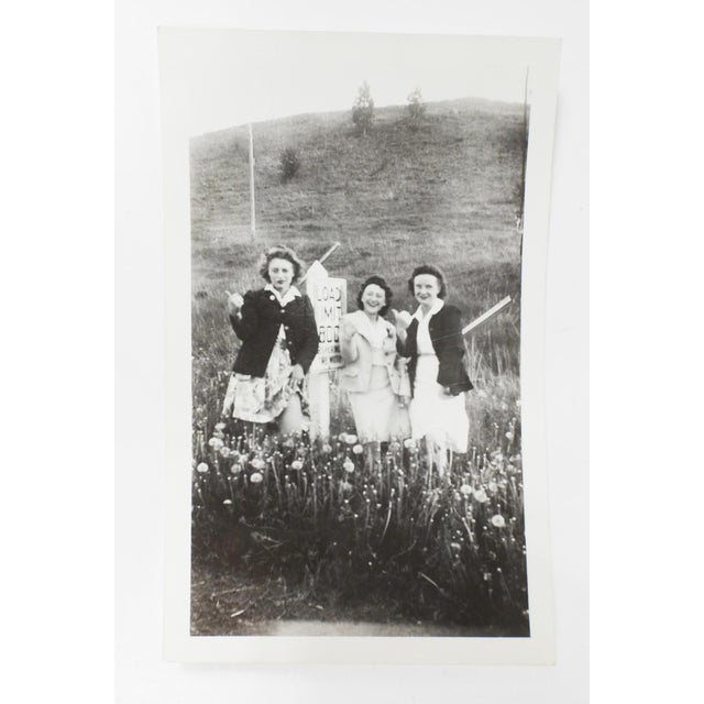 Mid 20th century snapshot photograph of three woman being silly and striking a hitchhiker pose. Unframed, corner bumps.