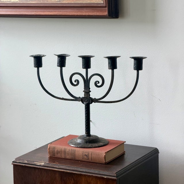 A dramatic five-arm iron candelabra with curled scrollwork, hammered texture, and a wonderfully timeworn blackened patina.