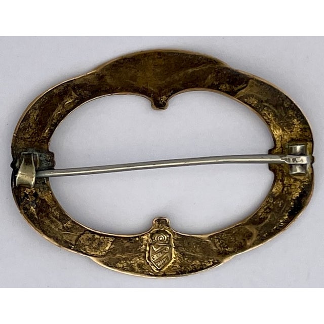 A handsome antique brass brooch with repose flourishes and floral design all around. There is a maker's mark that is hard...