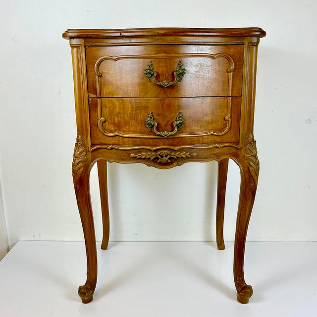 This is a lovely 1970s French Provincial Side Table or Nightstand with hand carved wood accents. The piece is walnut wood...