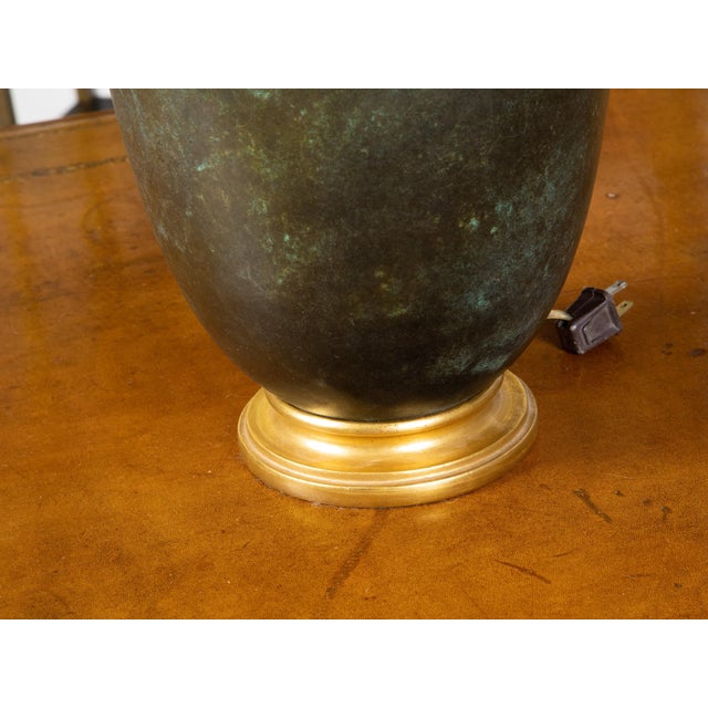A vintage English bronze two-light table lamp from the mid 20th century with horse heads, gilded base and verdigris...