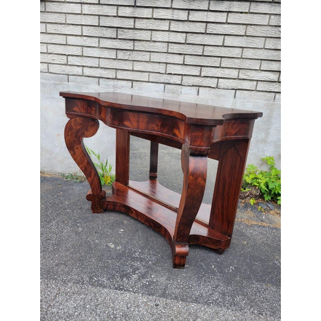 Stunning 1940s American Empire figured mahogany pier table, showcasing exceptional craftsmanship and classic style. The...