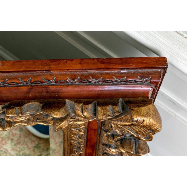 Exceptional 19th-century hand-carved mirror with an ornate giltwood and walnut-tone frame. The deep relief carving...