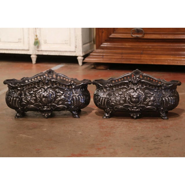 Richly sculpted in the Louis XV tradition, this pair of antique cast iron jardinières features an elegant combination of...