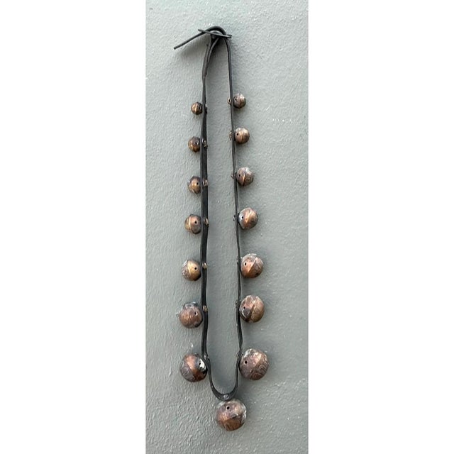 This vintage strand of sleigh bells is a long, graduated line of round bronze-toned bells mounted in pairs along a flat,...