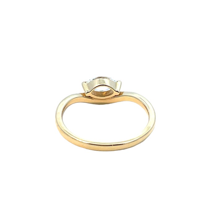 Elegant 18K yellow gold ring featuring a bezel-set marquise-cut diamond weighing approximately 0.53 carats. The ring...