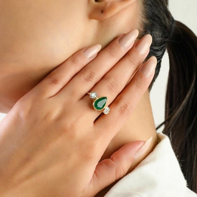 This elegant three-stone ring features 1 natural pear-shaped emerald totaling 2.29 carats, set in 18k yellow gold. The...