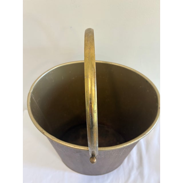 Vintage Mid-Century wastebasket featuring a faux woodgrain exterior with brass-tone interior and matching swing handle....