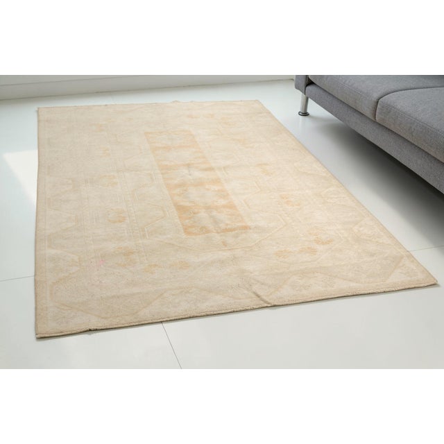 This is a vintage Turkish Oushak rug from the Mid 20th Century. The piece was hand-knotted.
