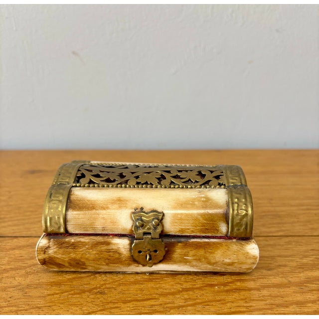 This vintage trinket box, crafted from bone and framed in warm brass, feels like something discovered at the back of a...