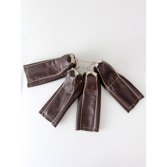 A set of four vintage 1950s golf club head covers in rich brown and cream, accented with metallic gold piping and...